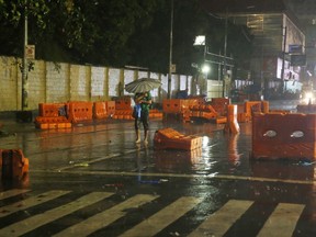A commuter walks to work amidst traffic barriers which were toppled by Typhoon Mangkhut which barrelled into northeastern Philippines before dawn Saturday, Sept. 15, 2018, in Manila, Philippines. Typhoon Mangkhut, the strongest typhoon to hit the country this year, slammed into the country's northeastern coast early Saturday that forced the evacuation of thousands of residents.
