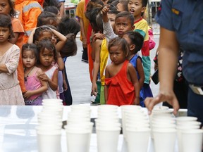 Residents living along the coastal community of Baseco wait to receive rice porridge as they seek temporary shelter at an evacuation centre during Typhoon Mangkhut on Saturday, Sept. 15, 2018 in Manila, Philippines.