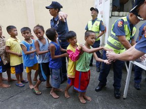 Manila police distribute rice porridge to residents living along the coastal community of Baseco as they evacuate during the onslaught of Typhoon Mangkhut which barreled into northeastern Philippines before dawn Saturday, Sept. 15, 2018 in Manila, Philippines. Philippine officials were assessing damage and checking on possible casualties as Typhoon Mangkhut on Saturday pummeled the northern breadbasket with ferocious wind and rain that set off landslides, damaged an airport terminal and ripped off tin roofs.