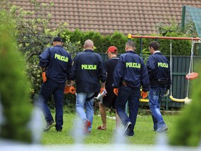 Slovenian police officers walk with politician Andrej Sisko, center, as they search five houses in the northeastern area around the town of Maribor, Slovenia, Thursday, Sept. 6, 2018. Slovenian police say they have arrested two people for paramilitary activity after video footage and photos surfaced on social media of a group of armed, masked men led by a right-wing former presidential candidate. (AP Photo)