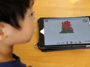 In this July 12, 2018, photo, a child works on a digital program at Coby Preschool in Yoshikawa, suburban Tokyo, on an assignment, which was to draw on a triangle on an iPad. For the kids, it's all about having fun. Japanese preschool programs equipped with tablet computers aim to prepare kids for the digital age.