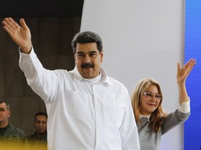 In this photo released by the Miraflores Press Office, Venezuela's President Nicolas Maduro, left, and his wife Cilia Flores greet supporters upon their arrival to a meeting with Colombian citizens that reside in Venezuela, In Caracas, Venezuela, Tuesday, Sept. 25, 2018. The Trump administration has slapped financial sanctions on four members of Venezuelan President Nicolas Maduro's inner circle, including his wife and the nation's vice president, on allegations of corruption. (Miraflores Press Office via AP)