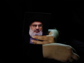A Lebanese Shiite supporter of the Iranian-backed Hezbollah group, holds a portrait of Hezbollah leader Sheikh Hassan Nasrallah, during activities to mark the ninth of Ashura, a 10-day ritual commemorating the death of Imam Hussein, in a southern suburb of Beirut, Lebanon, Wednesday, Sept. 19, 2018.