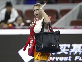 Simona Halep, of Romania waves to spectators after retiring with her back injury during her first round of the women's singles match against Ons Jabeur of Tunisia in the China Open tennis tournament in Beijing, Sunday, Sept. 30, 2018.