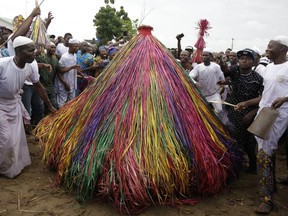 In this photo taken Saturday, Sept. 22, 2018, masquerades known as Zangbeto dressed in costumes, parade the street to mark the Ajido Voodoo festival in Nigeria.
