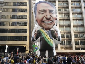FILE - In this Sept. 9, 2018 file photo, supporters of Jair Bolsonaro, presidential candidate for the National Social Liberal Party who was stabbed during a campaign event days ago, exhibit a large, inflatable doll in his image to show support for him, in Sao Paulo, Brazil. Silas Malafaia, one of Brazil's most influential pastors, visited Bolsonaro in the hospital. "God is an expert in turning chaos into a blessing," Malafaia said in a video he posted on YouTube from Bolsonaro's hospital room.