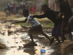 In this photo taken Monday, Sept. 17, 2018, children jump over raw flowing sewage on the streets of Harare, Zimbabwe. The sewage flows freely in the capital posing a deadly challenge to the recently elected president Emmerson Mnangagwa who has promised the country a new dawn.