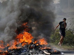 A Kosovo Albanian runs past a fire burning at a roadblock in Vojtesh, Kosovo, Sunday, Sept. 9, 2018. Kosovo Albanians burned tires and blocked roads with wooden logs, trucks and heavy machinery on a planned route by Serbia's President Aleksandar Vucic who was trying to reach the village of Banje while visiting Serbs in the former Serbian province.