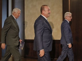 Turkey's Foreign Minister Mevlut Cavusoglu, center, walks with Polish Foreign Minister Jacek Czaputowicz, right, and Romanian Foreign Minister Teodor Melescanu, after a joint press conference in Bucharest, Romania, Tuesday, Sept. 11, 2018. The press conference concluded a trilateral foreign ministers meeting.