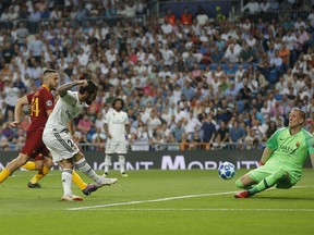 Roma goalkeeper Robin Olsen , right, defends a shot from Real midfielder Isco, 2nd from left during a Group G Champions League soccer match between Real Madrid and Roma at the Santiago Bernabeu stadium in Madrid, Spain, Wednesday Sept. 19, 2018.