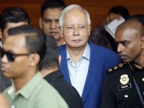 In this May 22, 2018, file photo, former Malaysian Prime Minister Najib Razak, center, arrives at Anti-Corruption Agency for questioning in Putrajaya, Malaysia. Malaysia's anti-graft agency says it has arrested former Najib over the multimillion-dollar looting of a state investment fund and that he will face further charges in court.  The agency says Najib was detained at its office on Wednesday, Sept. 14, and will be taken to court on Thursday to face the charges.