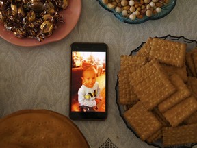 In this Aug. 23, 2018, photo, a phone displaying an image of one of Aziz's children, now missing, sits on a table surrounded by baked goods at his home in Istanbul, Turkey. Aziz, 37, was a surgeon in Hotan, China, before fleeing immediately after receiving a call from the police, leaving his wife and four children behind. The last thing he heard before losing contact with his family in mid-2017 was that his wife was sent to reeducation and three of his children were missing.