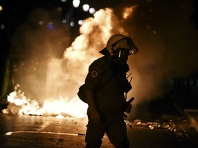 CORRECTING TO REMOVE REFERENCE TO ALLEGIANCE OF GROUP CLASHING WITH POLICE - A police officer walks in front of burning garbage cans during clashes with protesters in the northern Greek city of Thessaloniki, Saturday, Sept. 8, 2018.  Police in northern Greece have clashed with protesters outside an international trade fair where prime minister Tsipras made a keynote speech.