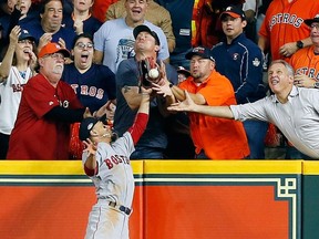 A fan interferes with Mookie Betts #50 of the Boston Red Sox as he attempts to catch a ball hit by Jose Altuve #27 of the Houston Astros (not pictured) in the first inning during Game Four of the American League Championship Series at Minute Maid Park on October 17, 2018 in Houston, Texas.