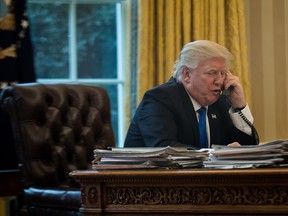 President Donald Trump speaks on the phone with Chancellor of Germany Angela Merkel in the Oval Office of the White House, January 28, 2017 in Washington, DC.