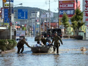 Soldiers ferry people to safety following heavy flooding, on July 8, 2018 in Kurashiki near Okayama, Japan.