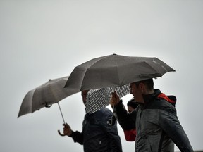 People shelter from the rain under their umbrellas, in San Sebastian, northern Spain, Sunday, Oct. 14, 2018. A weakened hurricane Leslie slammed into the coast of Portugal, leaving 27 people injured as it uprooted trees, brought down power lines and smashed store windows with gusting winds and heavy rain. Leslie moved east Sunday across the Iberian Peninsula to Spain, where authorities issued warnings for heavy rains and storm conditions for the northern part of the country.