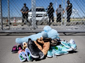This June 21, 2018 file photo shows security standing before shoes and toys left at the Tornillo Port of Entry in Tornillo, Texas where minors crossing the border without proper papers have been housed after being separated from adults.