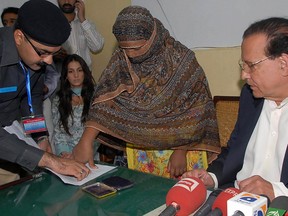 This file handout photograph taken on November 20, 2010 and released by the Directorate General Public Relations (DGPR) Punjab shows Pakistani Christian woman Asia Bibi (C) applying her thumb to appeal papers filed against her death sentence for blasphemy charges as the then-governor of Punjab Salman Taseer (R) looks on at the Central Jail in Sheikhupura. - Pakistan's Supreme Court on October 31, 2018 overturned the conviction of Asia Bibi, a Christian mother facing execution for blasphemy, in a landmark case which has incited deadly violence and reached as far as the Vatican.