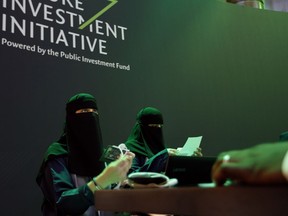 Saudi employees print badges of participants of the Future Investment Initiative conference, which kicks off Tuesday, in Riyadh, Saudi Arabia, Monday, Oct. 22, 2018. Saudi Arabia is moving ahead with plans to hold the glitzy investment forum, despite some of its most important speakers pulling out in the global outcry over the killing of Saudi journalist Jamal Khashoggi.