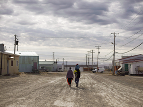 A family walks down the streets in Cambridge Bay, Nunavut — one of three communities affected by the supply barge cancellation.