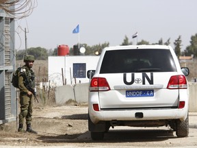 An Israeli soldier opens the border gates as an UN vehicle enters Syria in Quneitra crossing in the Israeli controlled Golan, Monday, Oct. 15, 2018. The crossing between Syria and the Israeli-occupied Golan Heights reopened for U.N. observers who had left the area four years ago because of the fighting there.