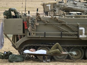 An Israeli soldier sleeps next to a military vehicle in a gathering point near Israel Gaza border, Friday, Oct. 19, 2018.