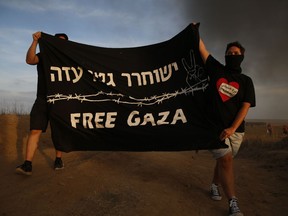 Israeli peace activists hold a banner during a protest on Israel Gaza border, Friday, Oct. 5, 2018. Writing in Hebrew reads "Free Gaza ghetto".