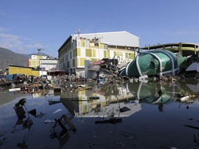 In this Sunday, Sept. 30, 2018, file photo, a damaged shopping mall sits in flood water following earthquakes and a tsunami in Palu, Central Sulawesi, Indonesia.