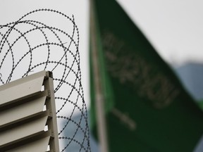 Behind barbed wire, Saudi Arabia's flag flies atop the country's consulate in Istanbul, Thursday, Oct. 18, 2018. Turkish crime-scene investigators finished an overnight search of both residence and a second search of the consulate itself amid Ankara's fears that Saudi writer Jamal Khashoggi was killed and dismembered inside the diplomatic mission in Istanbul.