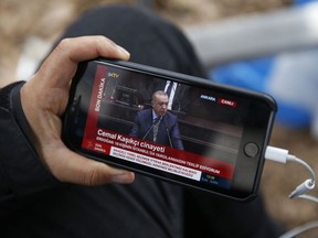 A journalist covering the killing of Saudi writer Jamal Khashoggi, watches a live transmission of Turkey's President Recep Tayyip Erdogan addressing members of his ruling Justice and Development Party (AKP), at the parliament in Ankara, Turkey, Tuesday, Oct. 23, 2018. Turkey's president says Saudi officials started planning to murder Saudi writer Jamal Khashoggi days before his death in Saudi Arabia's Istanbul consulate.