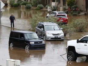 Vehicles caught during a flash flood wait to get towed from the waters on a local street as a result of heavy rains from tropical storm Rosa Tuesday, Oct. 2, 2018, in Phoenix.