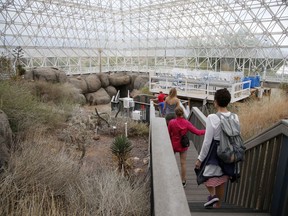 In this Friday, July 31, 2015, photo, tourists walk through the enclosed coastal fog desert ecosystem of the Biosphere 2 in Oracle, Ariz. Biosphere 2 lives on as a successful research site 25 years after eight people emerged from the New Age-style experiment in the Arizona desert.