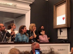 Onlookers watch as Banksy's work self-destructs.