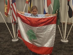 This Sept. 30, 2018 photo provides by Rochana Atmeh, shows Jennifer Maria Hektor, 8, born to a Swedish father and Rochana Atmeh, her Lebanese mother, holding a Lebanese flag, in Johannesburg, South Africa. Hektor won runner-up place in an international mental calculation competition in South Africa representing Lebanon. But the 8-year old doesn't have Lebanese citizenship. Human Rights Watch called on Lebanese authorities to amend a 1925 law that discriminates against Lebanese mothers, denying them the right to pass on citizenship to their children. (Rochana Atmeh via AP)