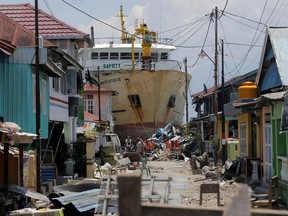 FILE - In this Tuesday, Oct. 2, 2018, file photo, a ship rests near houses after it was swept ashore during Friday's tsunami at a neighborhood in Donggala, Central Sulawesi, Indonesia. Five days after Indonesia's earthquake and tsunami devastated villages on Sulawesi island, residents hoping that help would soon arrive are angry because it hasn't.