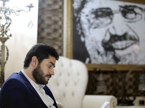 In this Sept. 30, 2018 photo, Abdullah Morsi, the youngest son of Egypt's jailed former Islamist President Mohamed Morsi, sits in front of a framed image of his father that was printed on a flag during the 2013 Rabaah al-Adawiya sit-in, at his home in Cairo, Egypt. Abdullah is campaigning for more access to and better treatment for his father. The former president has been held for years in isolation and Abdullah says he is suffering from poor health.