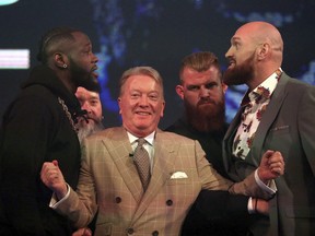 Deontay Wilder, left, and Tyson Fury, right, are kept apart by promoter Frank Warren during a press conference at BT Sport Studio, London, Monday, Oct. 1, 2018.