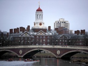 FILE - In this March 7, 2017 file photo, rowers paddle down the Charles River past the campus of Harvard University in Cambridge, Mass. A lawsuit alleging racial discrimination against Asian American applicants in Harvard's admissions process is heading to trial in Boston's federal court on Monday, Oct. 15, 2018. Harvard denies any discrimination, saying it considers race as one of many factors when considering applicants.