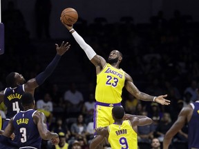 Los Angeles Lakers forward LeBron James (23) grabs a rebound over Denver Nuggets forward Paul Millsap (4) during the first half of an NBA preseason basketball game, Sunday, Sept. 30, 2018, in San Diego.