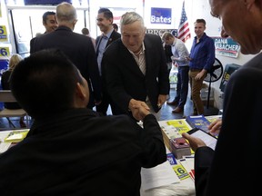 In this Oct. 17, 2018 image, California U.S. Rep. Dana Rohrabacher, center, greets supporters at party offices in Laguna Niguel, Calif. Thirty years ago, Rohrabacher campaigned for Congress as the face of the Reagan revolution. This year, locked in a tight race in a Southern California district much changed from the one where he first was elected, even a Republican Party mailer makes no mention of him being a Republican.