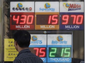 A man walks past Mega Millions and other lottery displays outside of The Lucky Spot in San Francisco, Thursday, Oct. 18, 2018. The Mega Millions jackpot has climbed to $970 million, inching ever-closer to the $1 billion mark.