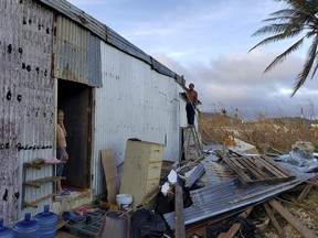 This photo released by Edwin Propst shows a man repairing damage to a home from Super Typhoon Yutu in Saipan, an island of the Northern Mariana Islands, Monday, Oct. 29, 2018. Elections are being postponed by a week in a Pacific U.S. territory still without electricity after a super typhoon destroyed homes, toppled trees, utility poles and left a woman dead.