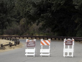 Signs indicate a road closure at the Malibu Creek State Park Thursday, Oct. 11, 2018, in Calabasas, Calif. Investigators will use ballistic testing to determine if a rifle carried by a burglary suspect was used in the killing of a camper at the California wilderness park. Authorities say 42-year-old Anthony Rauda had the gun and was dressed in black when he was arrested Wednesday after a search of a rugged canyon area near Malibu.