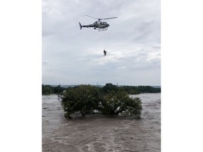 This photo from video provided by the Texas Parks and Wildlife Department shows a helicopter crew from the Texas Department of Public Safety performing a rescue from the South Llano River near Junction, Texas, on Monday, Oct. 8, 2018. Rescue crews in boats and helicopters are searching for several people missing since heavy rain washed away a recreational vehicle park in the small West Texas city. (Texas Parks and Wildlife Department via AP)