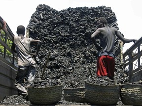 In this Tuesday Oct. 30, 2012 File photo, Somali porters offload charcoal from a truck at a charcoal market in Mogadishu, Somali. A new report by U.N. monitors says banned charcoal exports from Somalia are thriving, generating millions of dollars a year for al-Qaida-linked al-Shabab extremists.