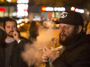 People smoke cannabis on the street in Toronto on Wednesday, Oct. 17, 2018. Canada became the largest country with a legal national marijuana marketplace as sales began early Wednesday in Newfoundland.
