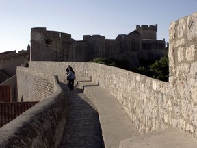 Tourists walk along the walls of the medieval city of Dubrovnik, on the Croatian Dalmatian Coast.