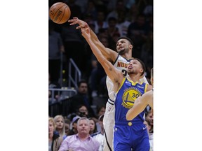 Denver Nuggets guard Jamal Murray (27) passes the ball away from Golden State Warriors guard Stephen Curry (30) during the first quarter of an NBA basketball game, Sunday, Oct. 21, 2018, in Denver.
