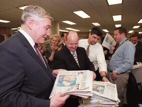 Conrad Black looks over a copy of the first edition of the National Post with Post staff in the Toronto newsroom on Oct. 27, 2018.